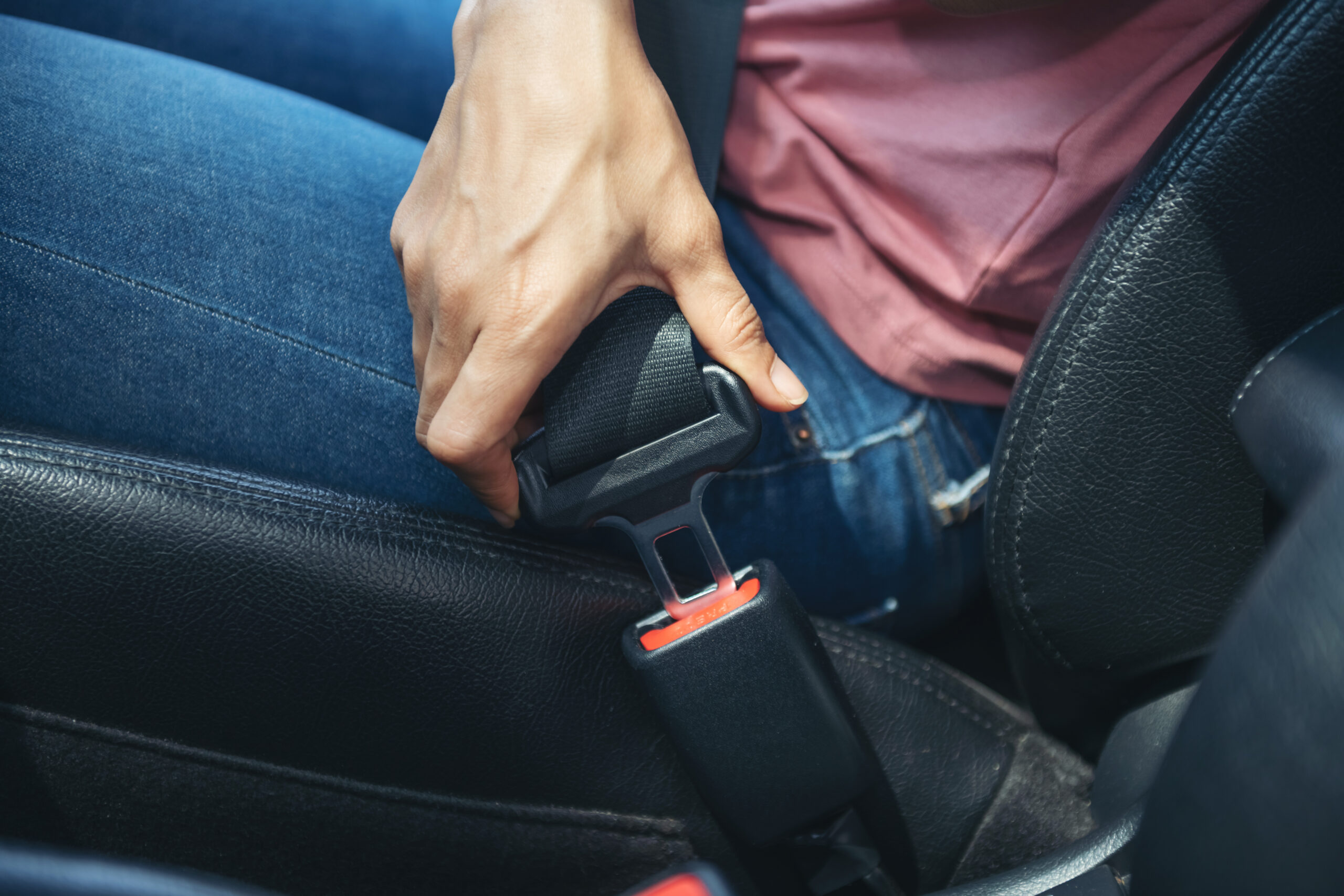 hand fastening a seatbelt in the car, Cropped image of a woman sitting in car and putting on her seat belt, Safe driving concept.